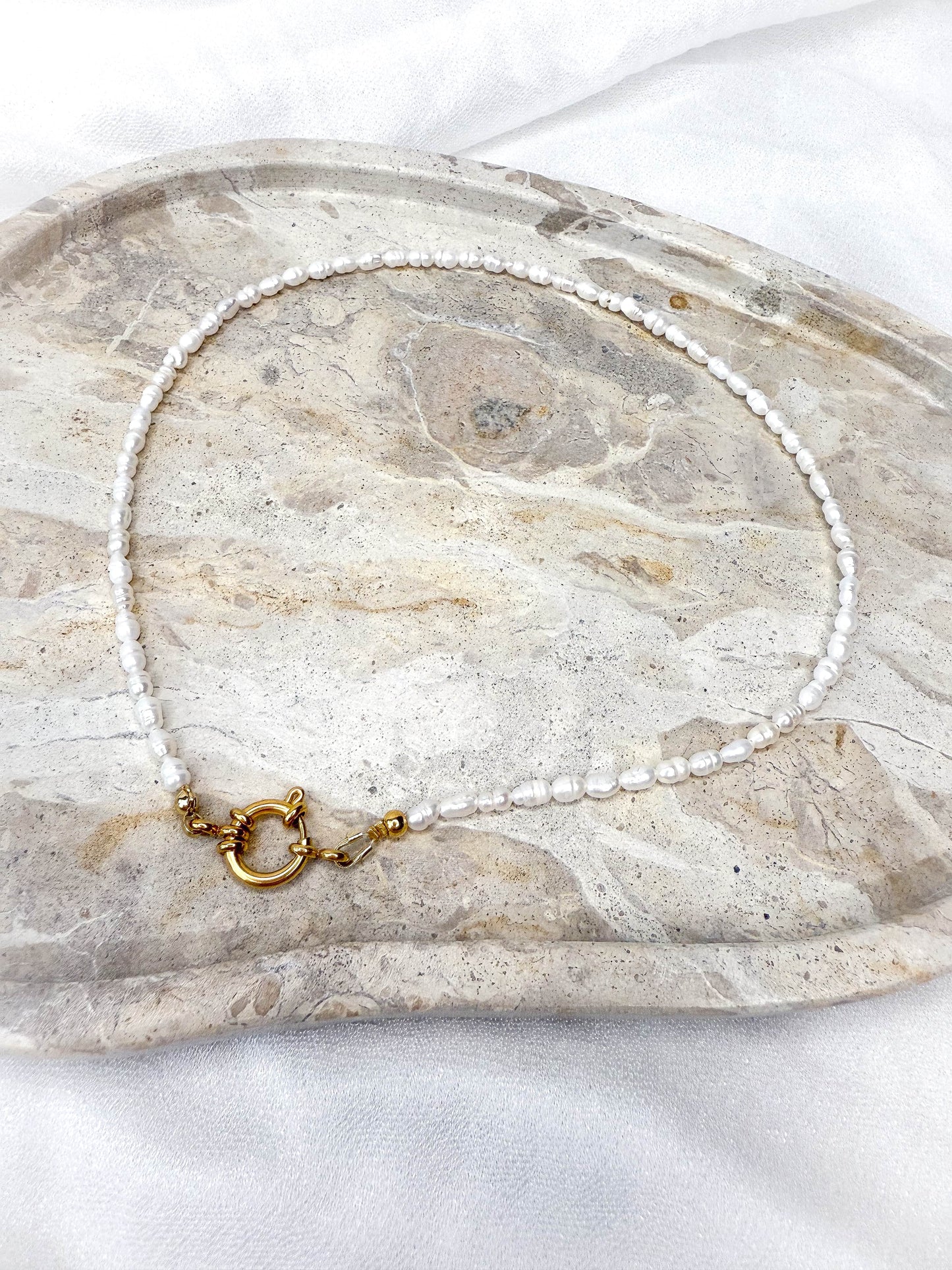 Handgefertigte Süßwasserperlen-Kette ‚Hannah‘ mit dekorativem Verschluss in Gold. Die elegante Perlenkette kann vielseitig getragen werden – mit dem Verschluss vorne als modernes Highlight oder klassisch nach hinten gedreht. Zeitloses Schmuckstück mit echten Süßwasserperlen, perfekt für jeden Anlass.